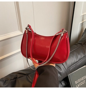 Detail of red glossy hobo bag with silver chain strap and sleek minimalist design