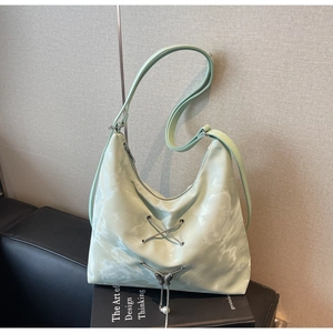 Detail of mint green tie-dye tote bag with metallic lacing and butterfly pearl charm