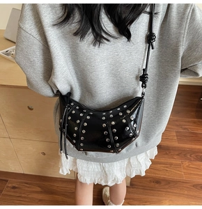 Dettaglio borsa a mezzaluna nera con borchie argentate e frange in pelle stile punk