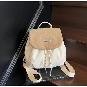 Close-up of white textured nylon backpack with khaki flap and YOU JI BEAR logo