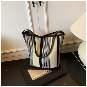 Close-up of black and white striped canvas tote bag with premium leather trim details