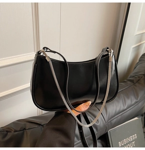Detail shot of the glossy black hobo bag with a silver metal chain and leather strap