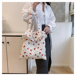 Detail of white mesh tote bag with red cherry pattern and ruffle trim shoulder strap