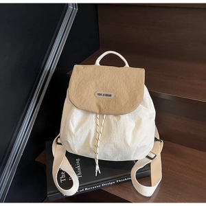 Detail of off-white textured backpack featuring a khaki flap and a brand logo on stairs