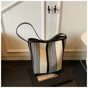 Detail of black and white striped tote bag with premium leather trim and shoulder strap