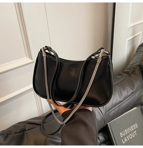 Detailed macro view of black glossy leather crescent bag with silver chain strap