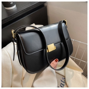 Close-up of a vintage black leather crossbody bag with a large golden square buckle