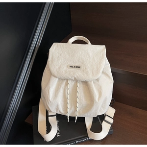 Close-up of white nylon drawstring backpack with brand patch on a wooden background