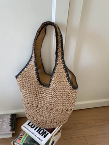 Large hand-woven straw tote bag with black contrast trim for summer beach vacations