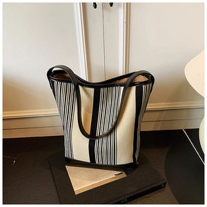 Detail of striped canvas tote bag with black faux leather straps and vertical pattern