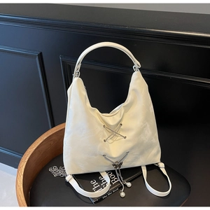 Close-up of white crescent tote bag with metal cross-lace and pearl butterfly charm detail