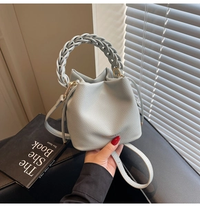 Close-up of light blue bucket bag featuring woven handle and textured lychee leather grain