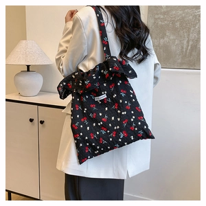 Detail of black mesh tote bag with cherry floral print and ruffle edges on the strap