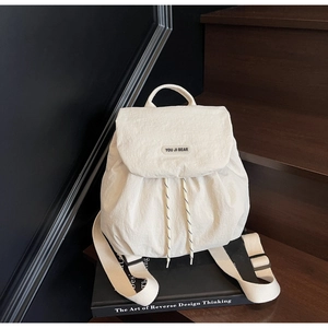 Detail of white nylon backpack featuring drawstring closure and brand logo on the flap