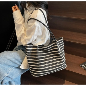 Close-up of black and white woven tote bag texture with slim leather shoulder straps