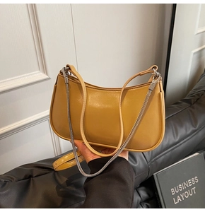 Detail of ginger yellow half-moon shoulder bag with sleek leather and silver metal chain