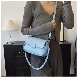 Detail view of the light blue crossbody bag with dual straps and pebbled leather texture