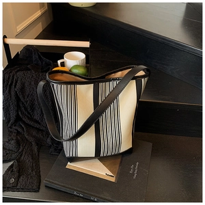 Detail of striped bucket bag showing canvas texture and black leather stitching detail