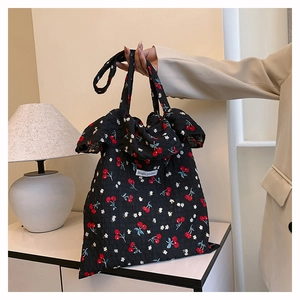 Detail of black mesh tote bag featuring red cherry prints and ruffled edges decoration