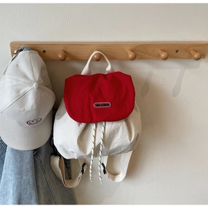 Detail of red and cream child backpack showing drawstring closure and brand label
