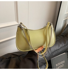 Detail of light green hobo bag featuring a silver metal chain and smooth leather texture