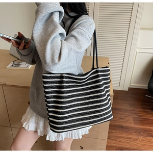 Detailed close-up of a woven black and white striped tote bag with slim black straps