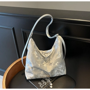 Detail of silver metallic hobo bag with lace-up design and pearl butterfly charm