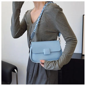 Detail of light blue crossbody bag with woven texture and thick braided shoulder strap