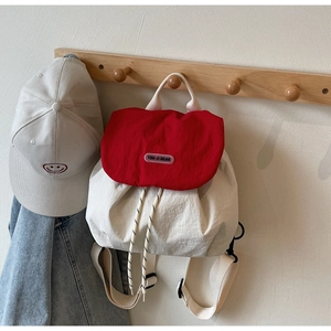 Detail of red and white nylon backpack hanging on a hook with adjustable woven straps