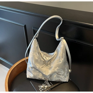 Detail showing metallic silver marble texture with crisscross straps and pearl charms on bag