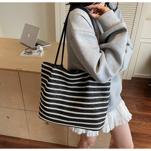 Close-up of a woven tote bag featuring black and white horizontal stripes and slim straps