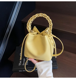 Detail of yellow bucket bag featuring woven handle, drawstring closure, and lychee texture