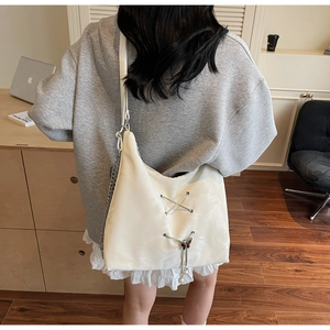 Detail view of cream tote bag featuring silver cross lacing and butterfly pearl pendant