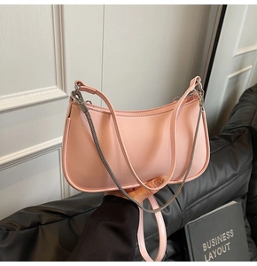 Detail of light pink crescent baguette bag with leather strap and silver chain decoration