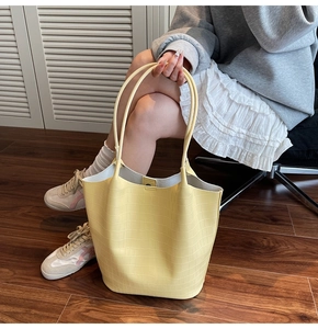 Detail shot of pale yellow crocodile texture bucket bag with long shoulder straps