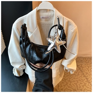 Détail d'un sac demi-lune plissé noir brillant avec un pendentif étoile argentée chic