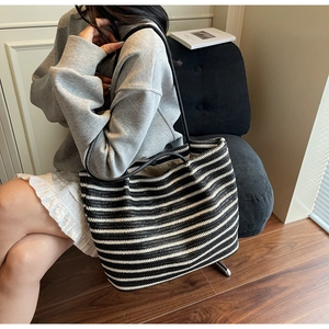 Detail shot of black and white striped woven tote bag with slim shoulder strap texture