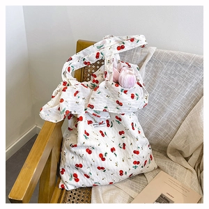 Close-up of white tote bag with red cherry print on a wooden chair with mesh fabric
