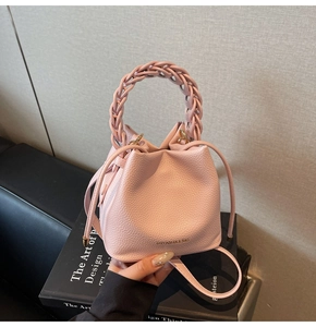 Detail of pink pebbled leather bucket bag with woven handle on an art book display