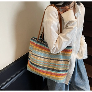 Lifestyle shot of colorful woven rainbow tote bag with leather straps on model shoulder