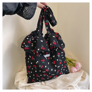 Close-up of black floral mesh tote bag featuring cherry patterns and Magic Pocket label