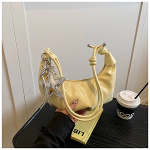 Détail du sac croissant plissé jaune crème avec breloque étoile argentée et chaîne