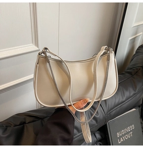 Detail of off-white crescent underarm bag with smooth texture and silver chain