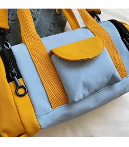 Detail of color-block barrel bag with yellow strap featuring BEAR text and zipper closeup