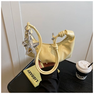 Détail du sac demi-lune plissé jaune clair avec breloque étoile de mer et anse nouée