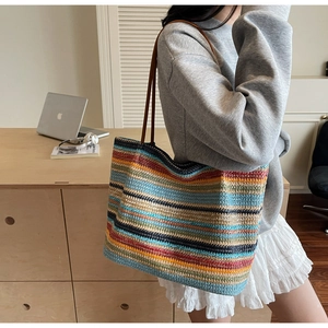 Detailed view of colorful woven tote bag featuring striped patterns and slim leather straps