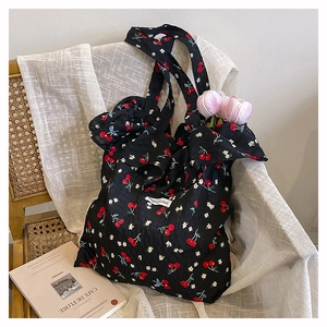 Close-up of floral cherry print tote bag with ruffled edges on a vintage wicker chair