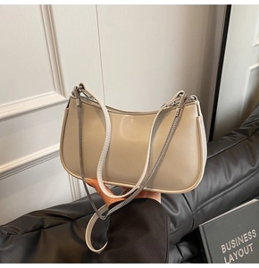 Close-up of cream white leather baguette bag with silver chain detail and smooth texture