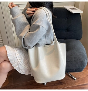 Detail shot of cream white bucket bag featuring elegant crocodile embossed texture
