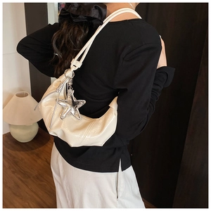 Détail du sac croissant plissé crème avec breloque étoile de mer sur l'épaule